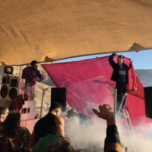 אנשים מניפים צילייה מעל רקדנים במדבר